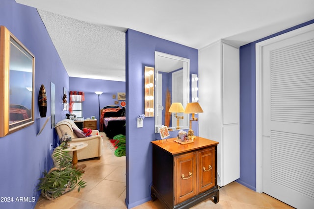 corridor featuring a textured ceiling and light tile patterned floors