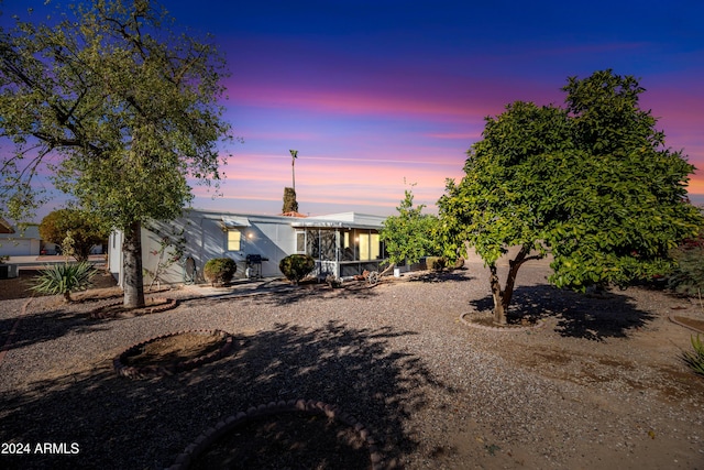 back house at dusk with a sunroom