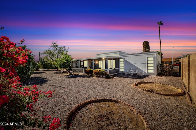 back house at dusk featuring a sunroom