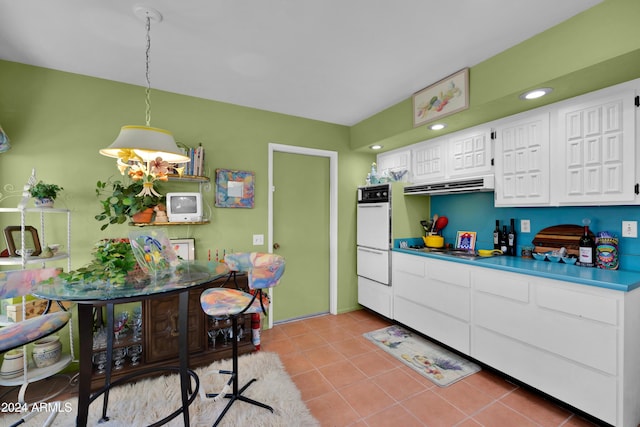 kitchen featuring white cabinetry, pendant lighting, white double oven, and light tile patterned flooring