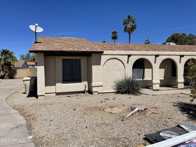 view of front facade featuring roof with shingles and stucco siding