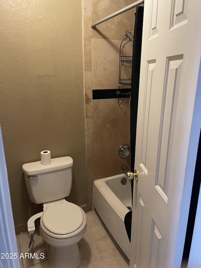 bathroom featuring toilet, shower / tub combo, tile patterned flooring, and a textured wall