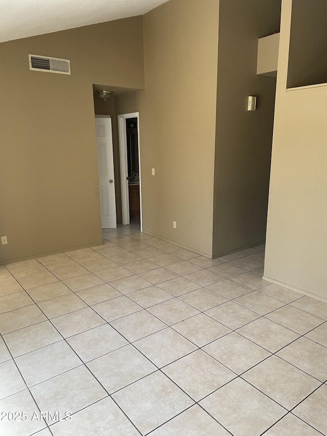 empty room with visible vents, vaulted ceiling, and light tile patterned floors