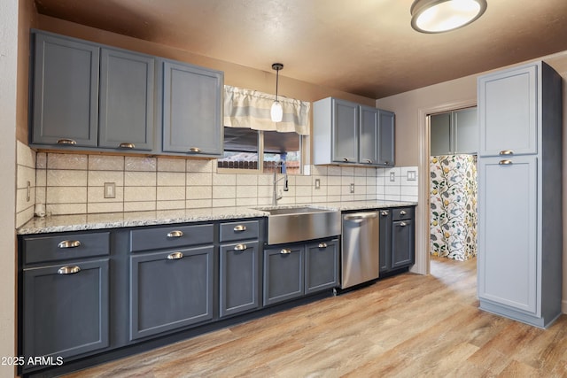 kitchen featuring pendant lighting, tasteful backsplash, gray cabinetry, stainless steel dishwasher, and light hardwood / wood-style flooring