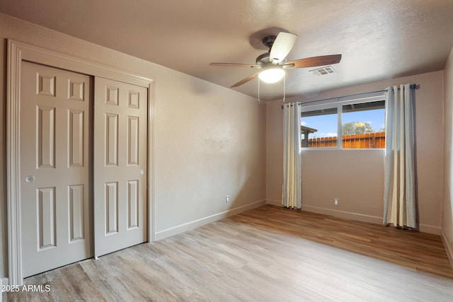 unfurnished bedroom featuring ceiling fan, light hardwood / wood-style floors, and a closet