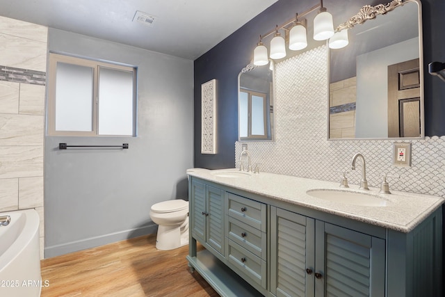 bathroom with hardwood / wood-style flooring, vanity, a bathing tub, and toilet