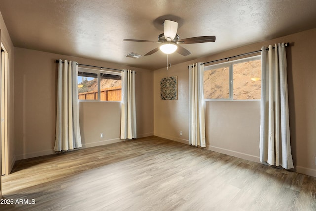 empty room featuring ceiling fan, light hardwood / wood-style flooring, and a textured ceiling