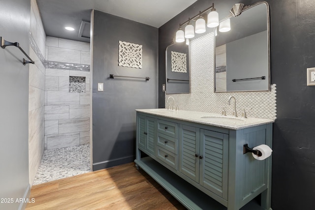 bathroom with tasteful backsplash, wood-type flooring, vanity, and a tile shower