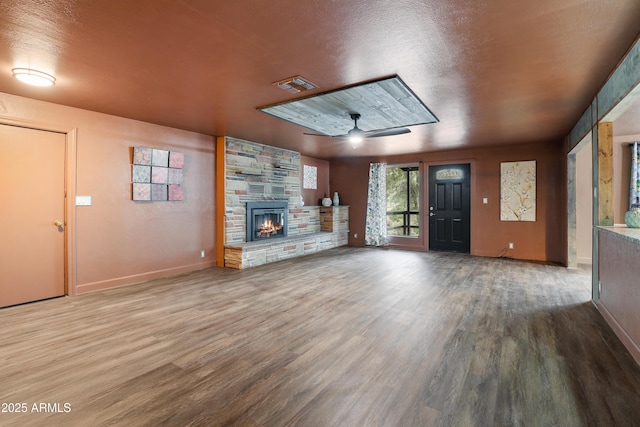 unfurnished living room with hardwood / wood-style flooring, ceiling fan, a fireplace, and a textured ceiling