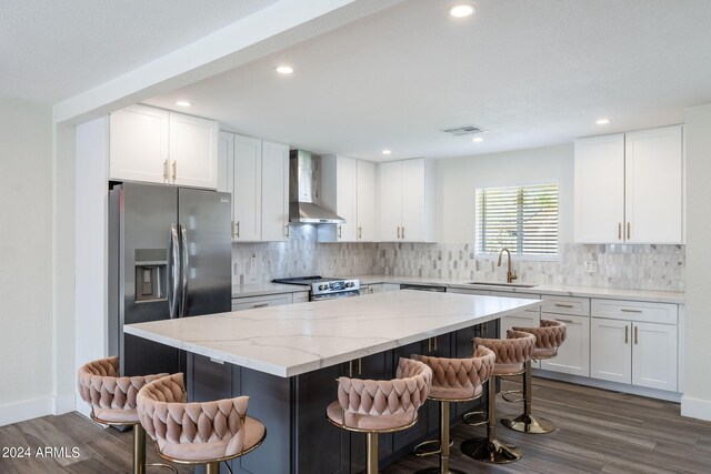 kitchen featuring a breakfast bar, white cabinetry, wall chimney exhaust hood, and a kitchen island