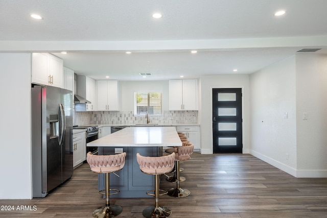 kitchen with white cabinets, tasteful backsplash, stainless steel fridge with ice dispenser, a center island, and wall chimney range hood