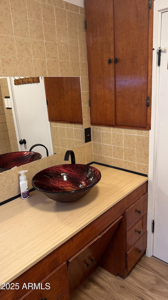 bathroom with wood-type flooring, vanity, and tasteful backsplash