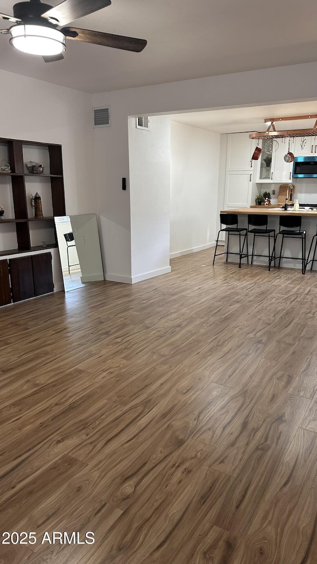 living room featuring dark hardwood / wood-style floors, ceiling fan, and sink