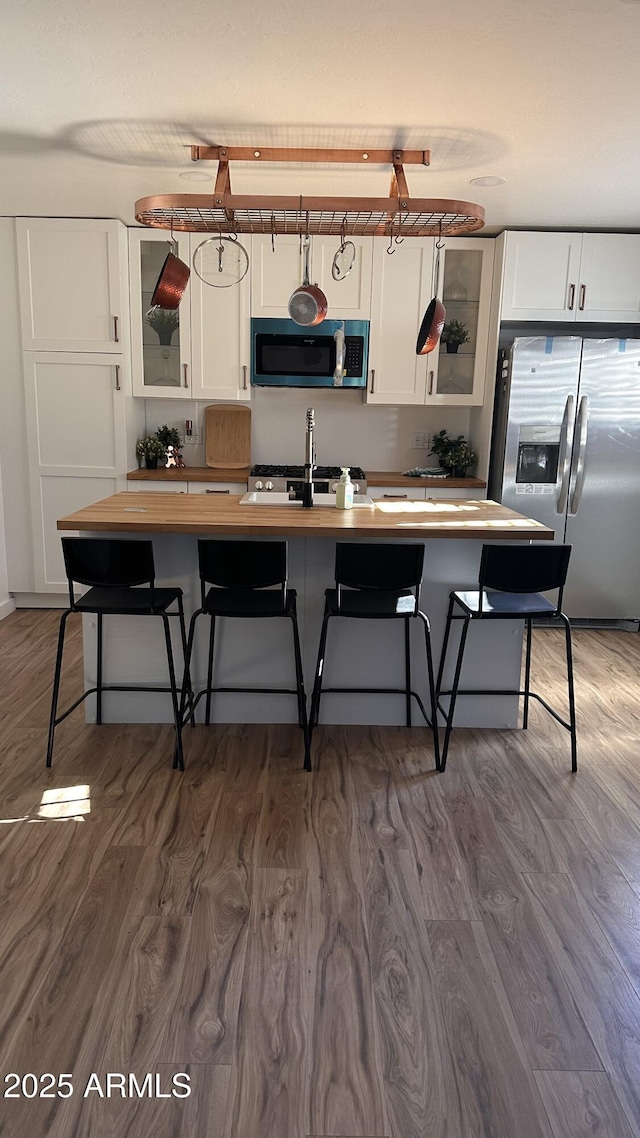 kitchen featuring dark hardwood / wood-style flooring, a breakfast bar, white cabinets, and stainless steel appliances