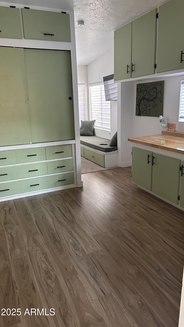 kitchen featuring wood counters, dark wood-type flooring, a textured ceiling, and green cabinetry