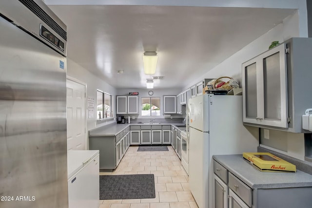 kitchen with light tile patterned floors, stainless steel appliances, gray cabinets, and sink