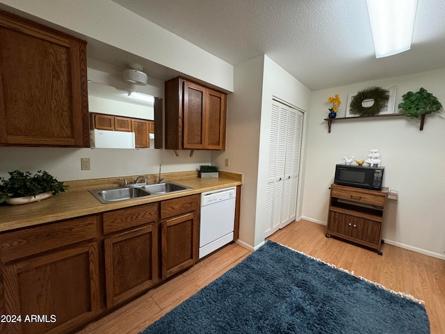 kitchen with dishwasher, light hardwood / wood-style floors, a textured ceiling, and sink