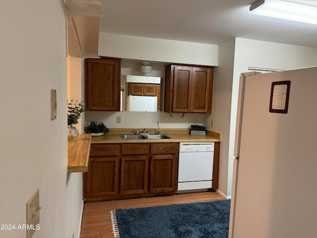 kitchen with sink, refrigerator, white dishwasher, a textured ceiling, and light wood-type flooring