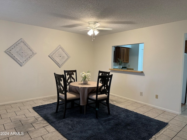 dining area featuring ceiling fan, light tile patterned flooring, and a textured ceiling