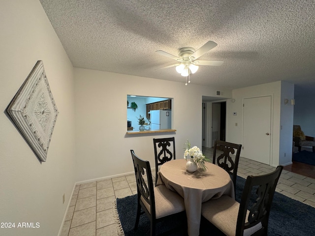 dining area with ceiling fan, light tile patterned floors, and a textured ceiling