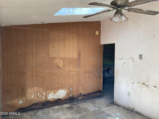 empty room with vaulted ceiling and wood walls