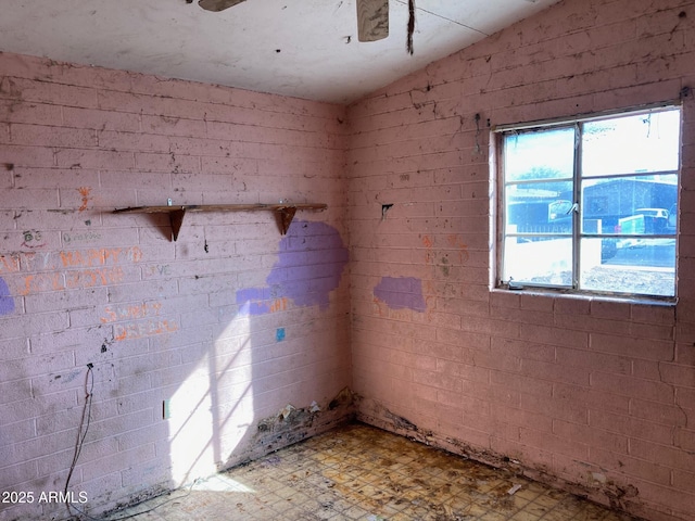 unfurnished room featuring brick wall