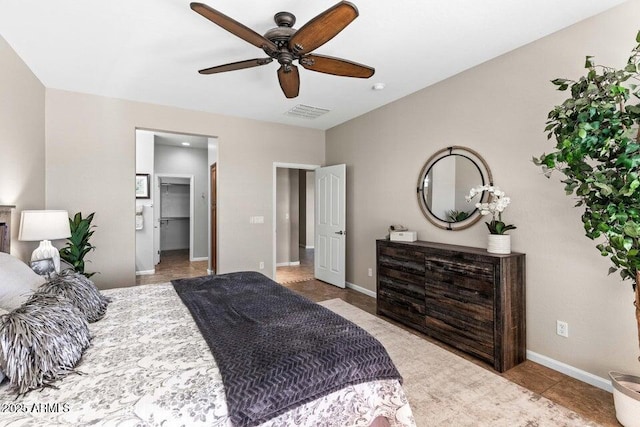 tiled bedroom with a spacious closet and ceiling fan