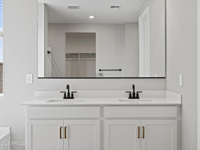 bathroom with double vanity, a sink, and visible vents