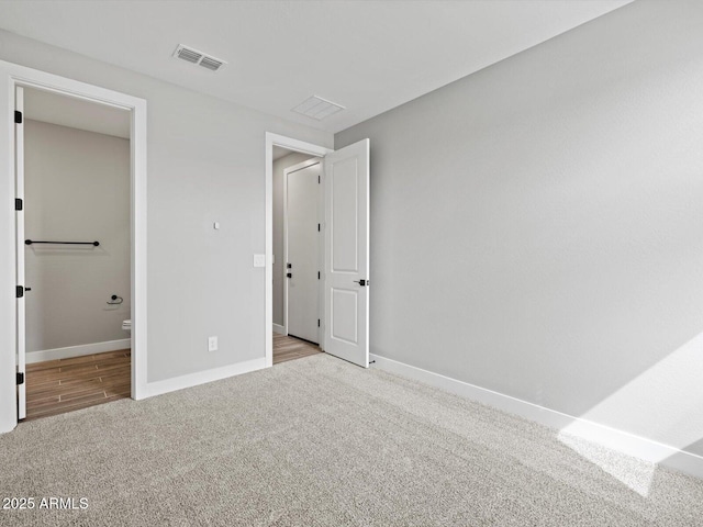 unfurnished bedroom with baseboards, visible vents, ensuite bath, and carpet flooring