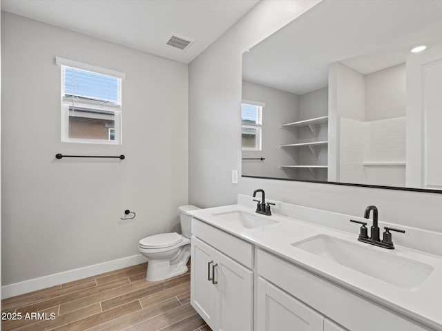 full bath with wood finish floors, a sink, visible vents, and baseboards