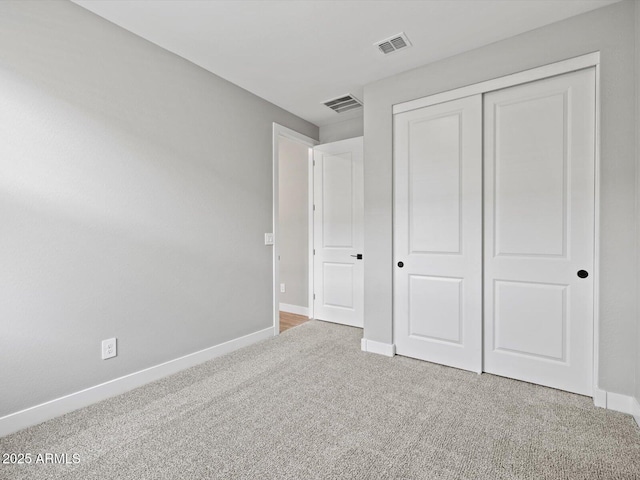 unfurnished bedroom featuring a closet, carpet flooring, visible vents, and baseboards