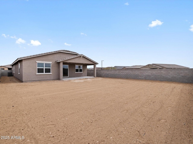 back of house featuring a fenced backyard, a patio, and stucco siding