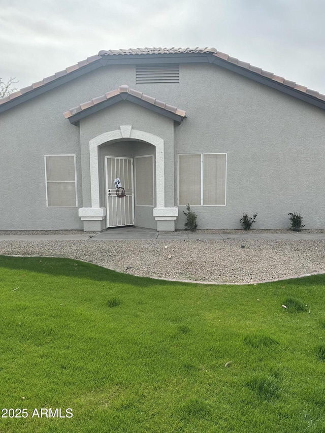 exterior space with a tile roof, a yard, and stucco siding