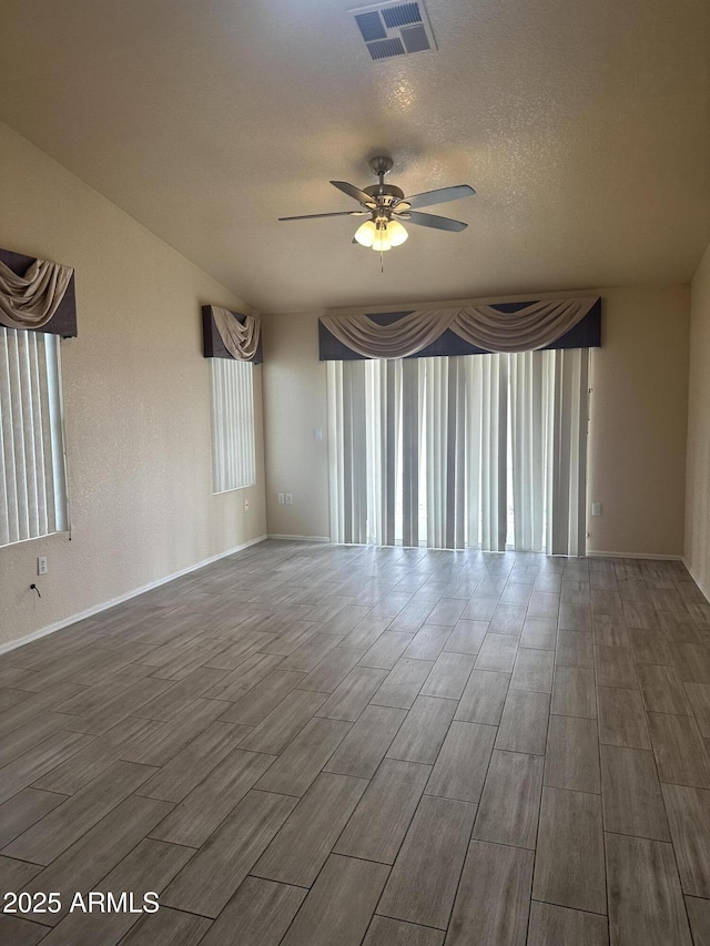 unfurnished room with visible vents, a ceiling fan, a textured ceiling, baseboards, and wood tiled floor