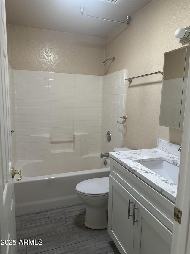 full bath with toilet, wood finished floors, shower / washtub combination, vanity, and a textured wall