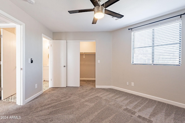 unfurnished bedroom featuring carpet floors, ceiling fan, a walk in closet, and a closet