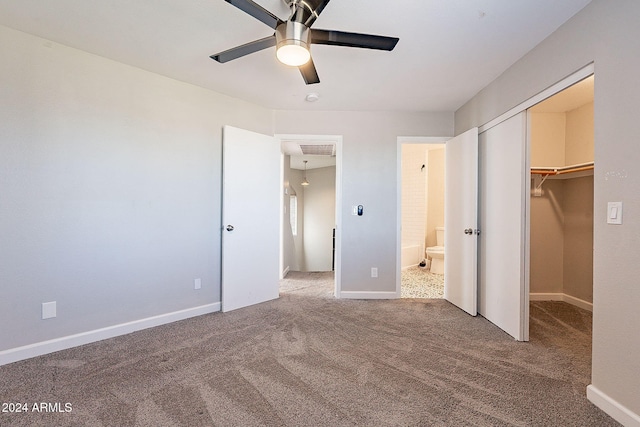 unfurnished bedroom with a closet, carpet, a spacious closet, and ceiling fan