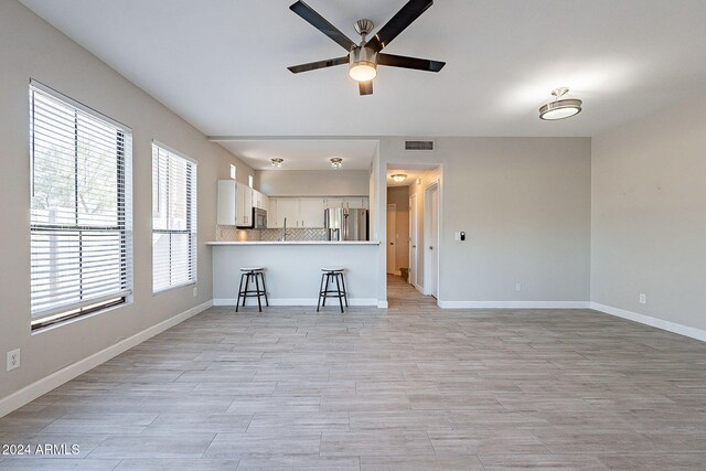 unfurnished living room featuring ceiling fan and a healthy amount of sunlight