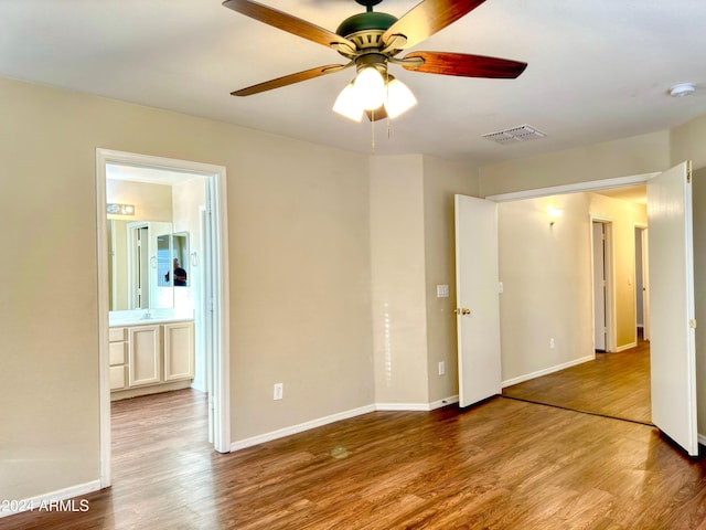 unfurnished bedroom with hardwood / wood-style floors, connected bathroom, and ceiling fan