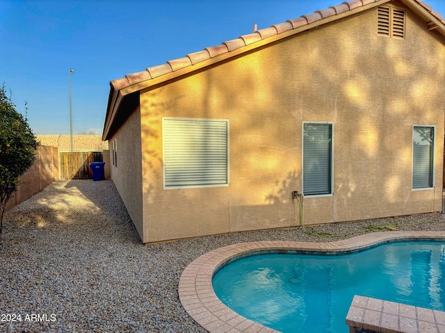 rear view of property with a fenced in pool