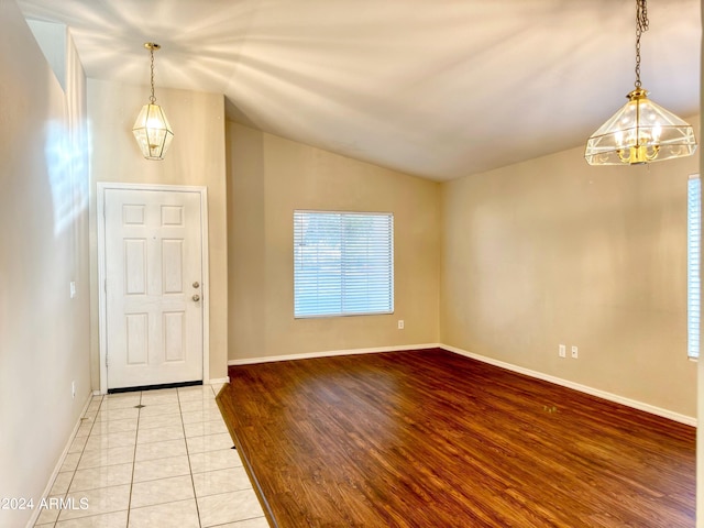 foyer with light wood-type flooring, vaulted ceiling, and a notable chandelier