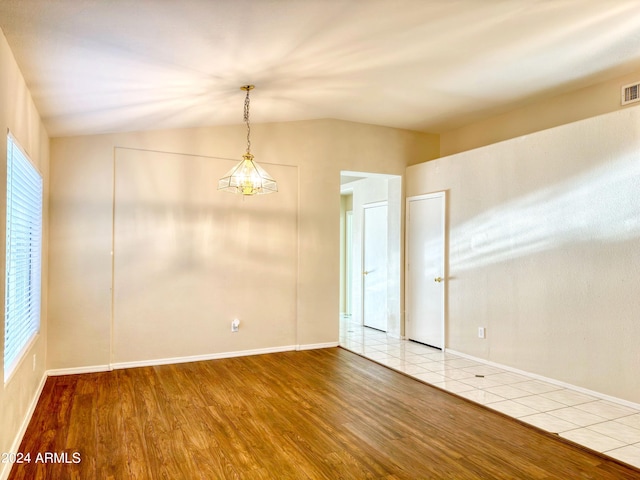 unfurnished room featuring vaulted ceiling, hardwood / wood-style flooring, and an inviting chandelier