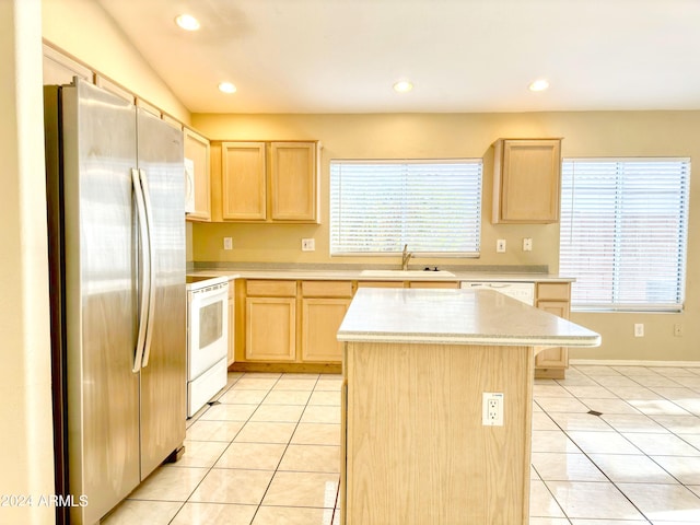 kitchen with light brown cabinets, white appliances, a kitchen island, and a healthy amount of sunlight