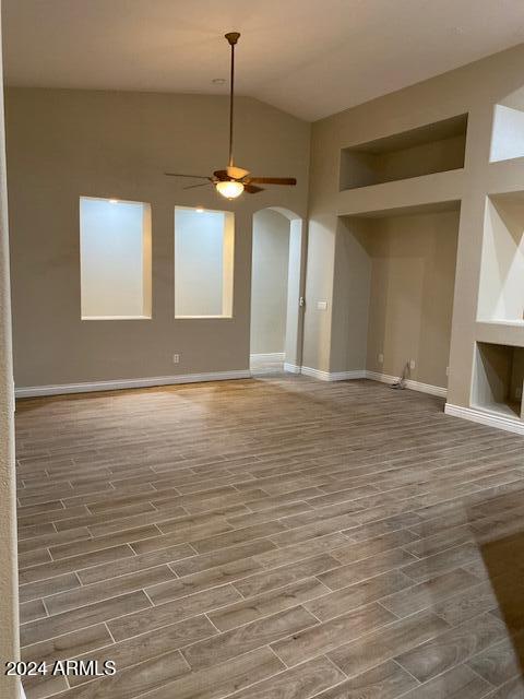 unfurnished living room featuring lofted ceiling, ceiling fan, and wood-type flooring