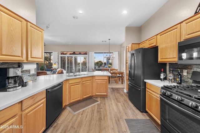 kitchen featuring black appliances, decorative backsplash, light wood-type flooring, decorative light fixtures, and kitchen peninsula