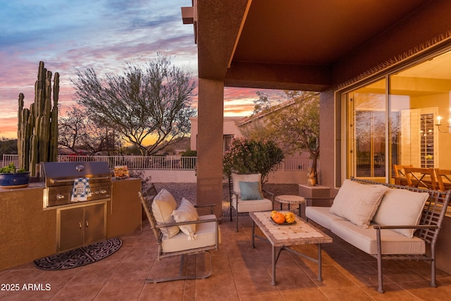 patio terrace at dusk featuring an outdoor living space, an outdoor kitchen, and grilling area