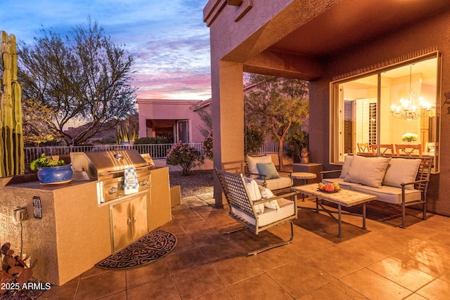 patio terrace at dusk with outdoor lounge area, an outdoor kitchen, and grilling area