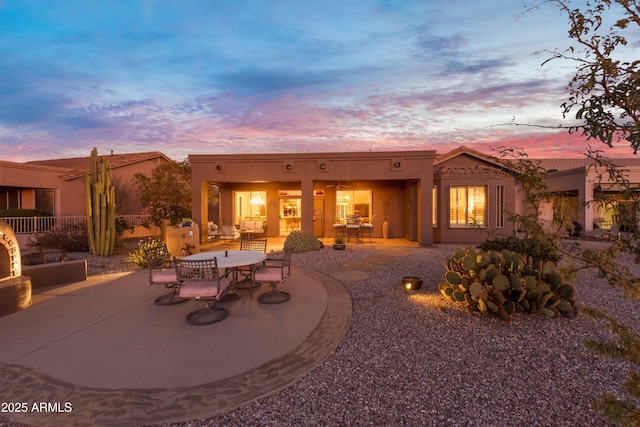 back house at dusk featuring a patio area