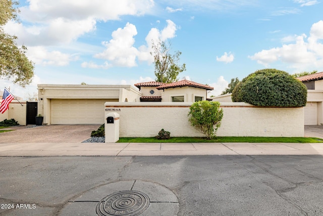 mediterranean / spanish home featuring a fenced front yard, concrete driveway, and stucco siding