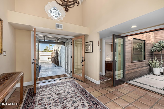 tiled entryway featuring french doors and a notable chandelier